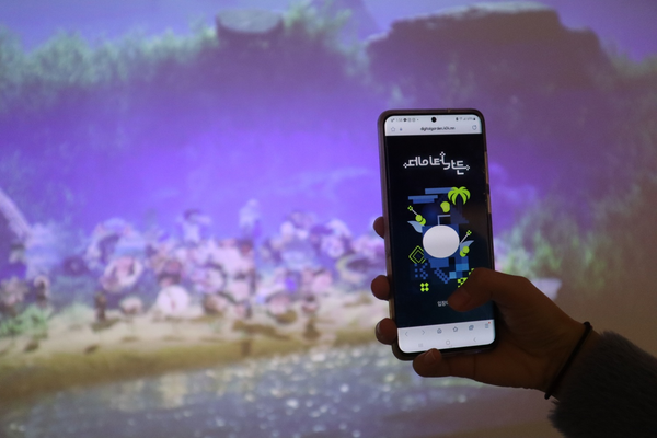 A phone showing the main screen of the app. Behind the phone is the video projection of a glowing garden.