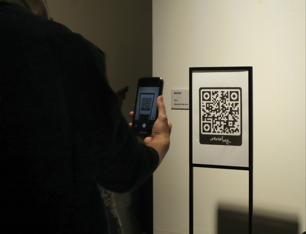 A person holds up a phone to scan the QR code.